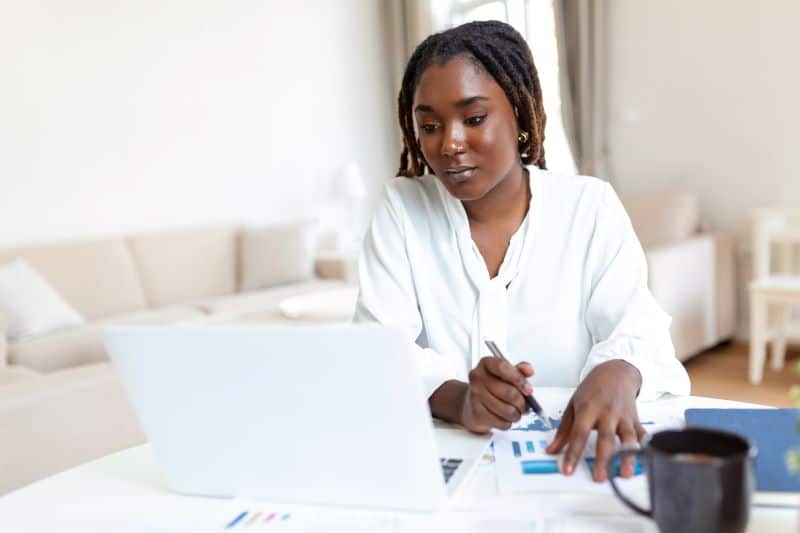 Empresária em home office lendo no computador sobre o que é conciliação bancária.