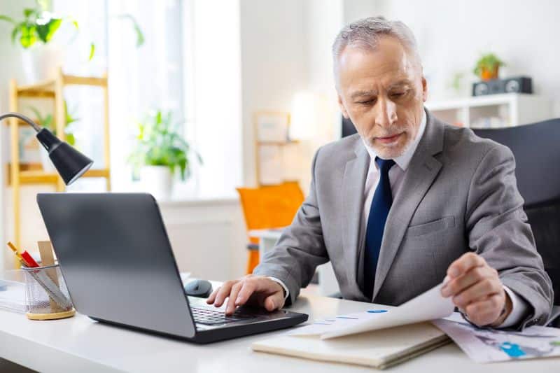 qual o regime de juros praticados em boletos​: homem de terno trabalhando em escritório verificando boleto