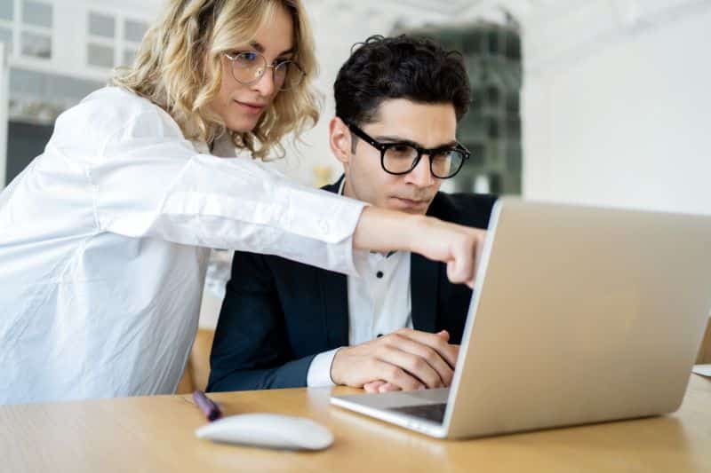 modelagem financeira​​: mulher apontando na tela do computador para colega no escritório