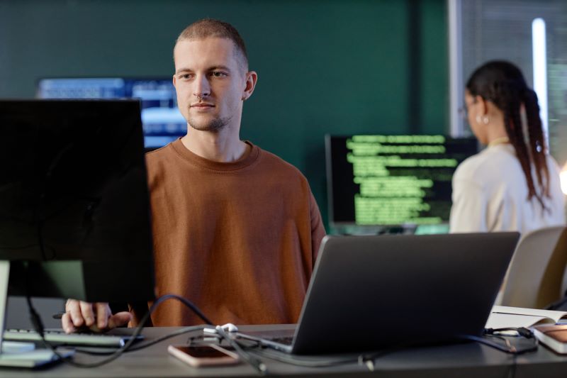 churn involuntário: homem trabalhando em escritório com vários computadores ao redor